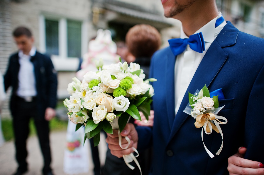 sposo-in-giacca-blu-e-papillon-con-bouquet da donare alla sposa